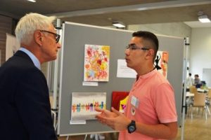 B'shayno-Mitglied Eilom Keriakos zeigt Martin Pantke, 2. stellvertretender Bürgermeister der Stadt Paderborn, Kunstwerke, die bei kreativen Projekten entstanden sind. (Quelle: AJM e.V./djoNRW)